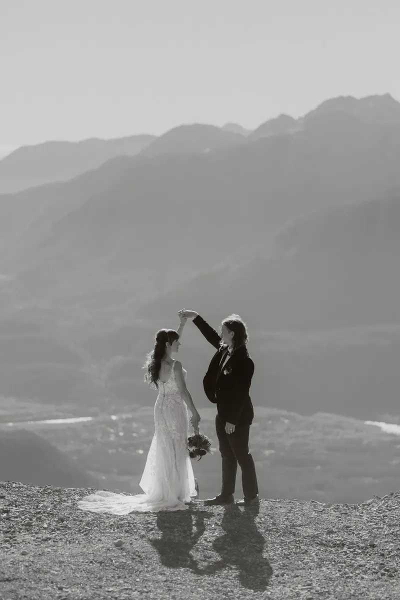 Groom twirling the bride on a mountain overlook, in black and white