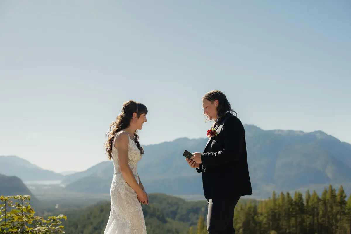 Couple exchanging vows on a mountaintop overlooking the valley