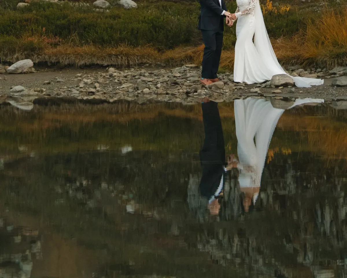 Couple reflected in a still mountain pond