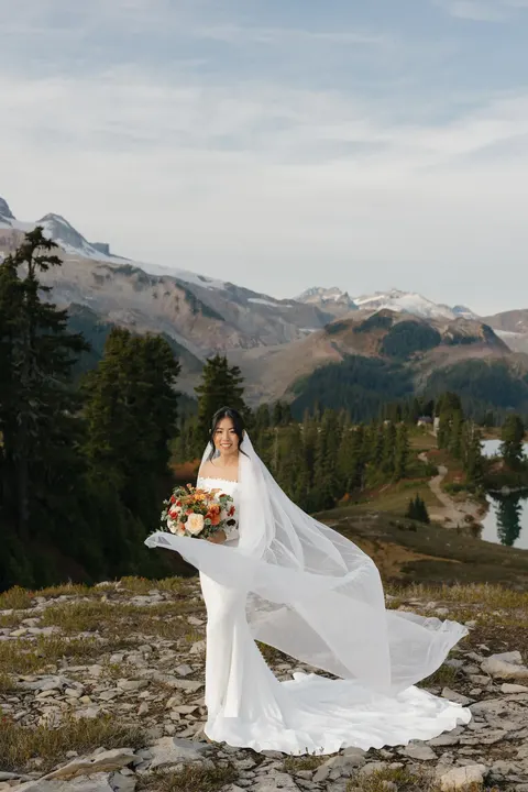 Bride on an alpine ridge with her veil blowing in the wind