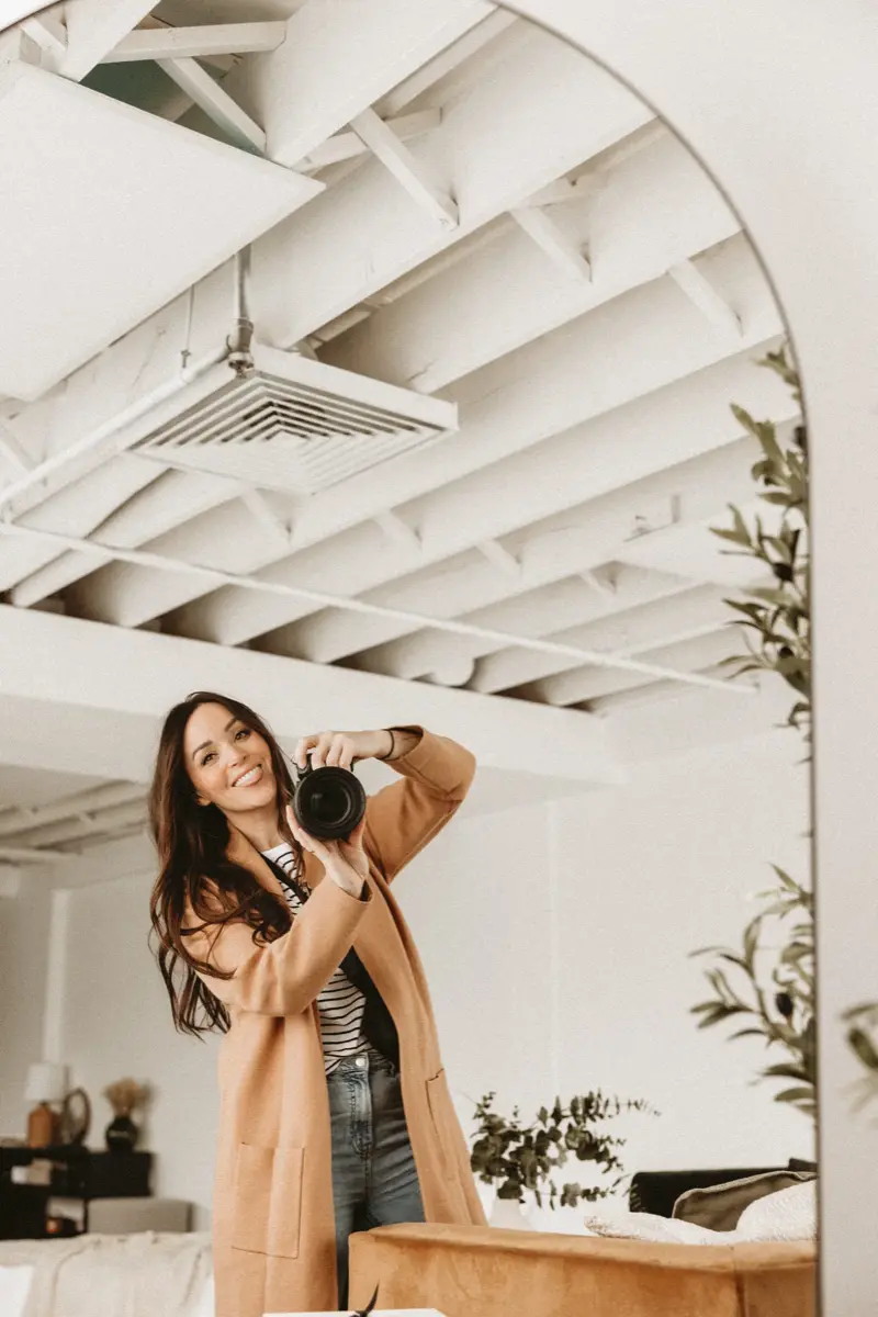 Stacey holding her camera in her bright studio