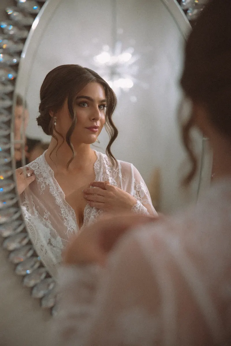 Bride reflected in an ornate mirror as she gets ready