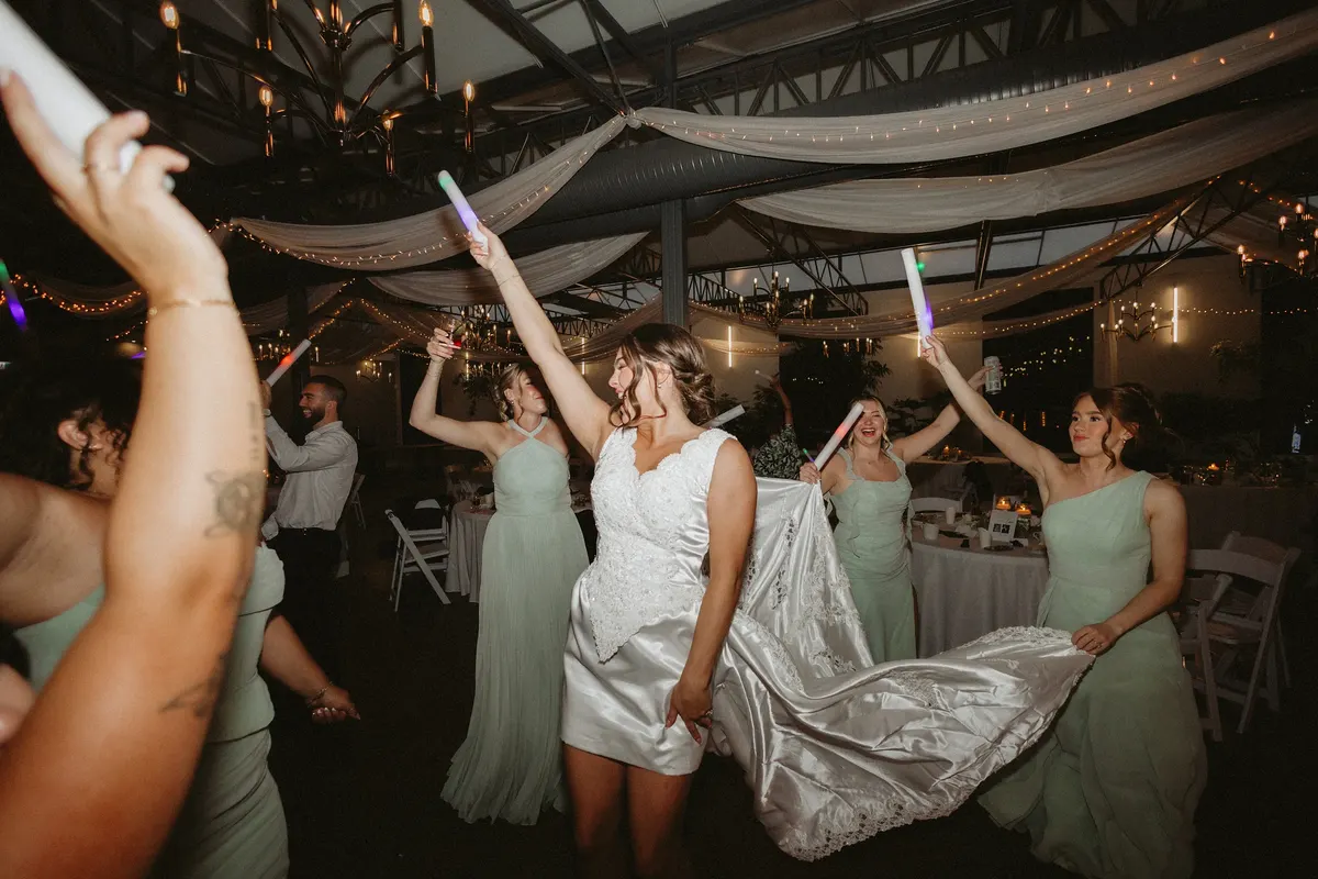 Bride dancing with her bridesmaids under the reception lights