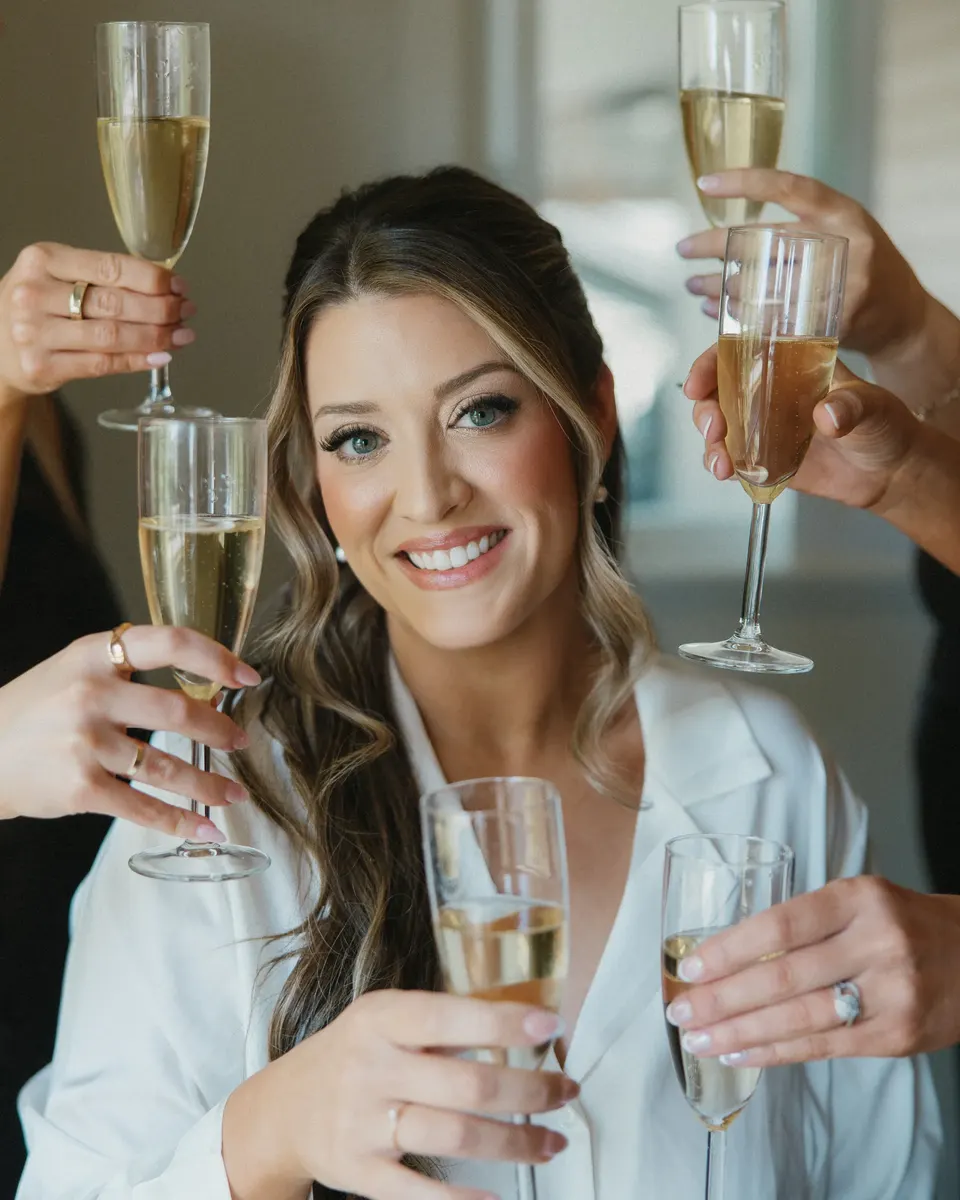 Bride raising a glass of champagne with her friends while getting ready