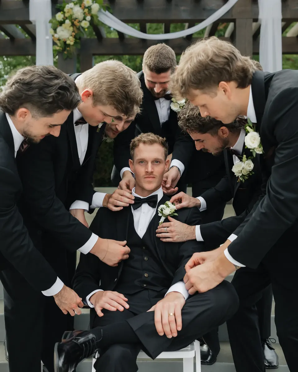 Groomsmen crowding around the groom to straighten his jacket
